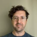 Henrik Söke, founder of Crystal Cleanse, in round glasses and a blue sweater, smiling slightly at the camera